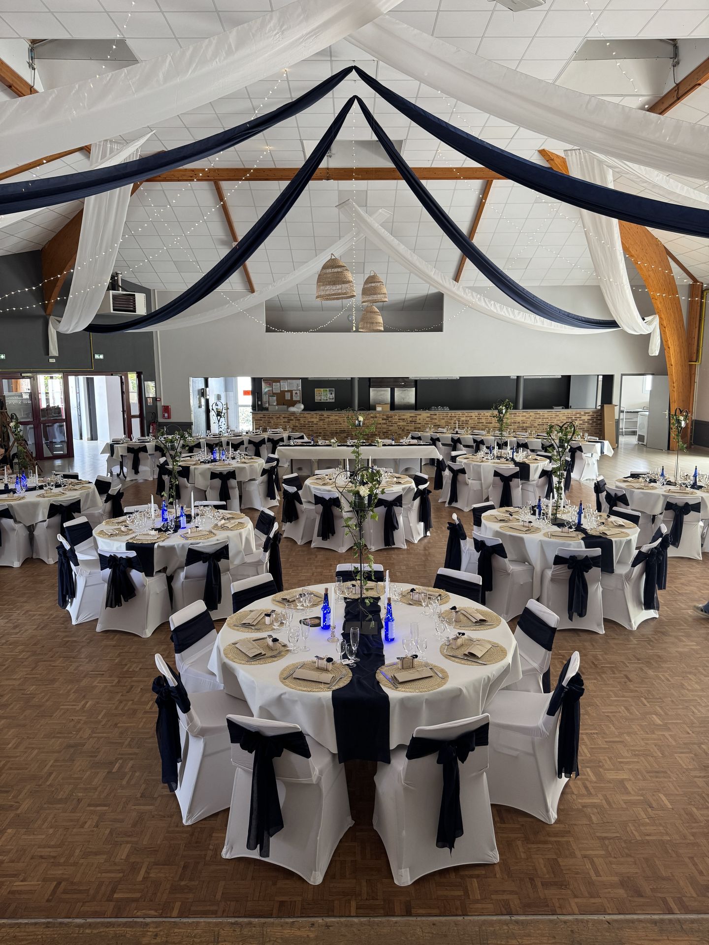 Mariage Espace de la Roche salle intérieur plafond tentures bleu marine et blanche leds table blanche noeud bleu marine et détails sables