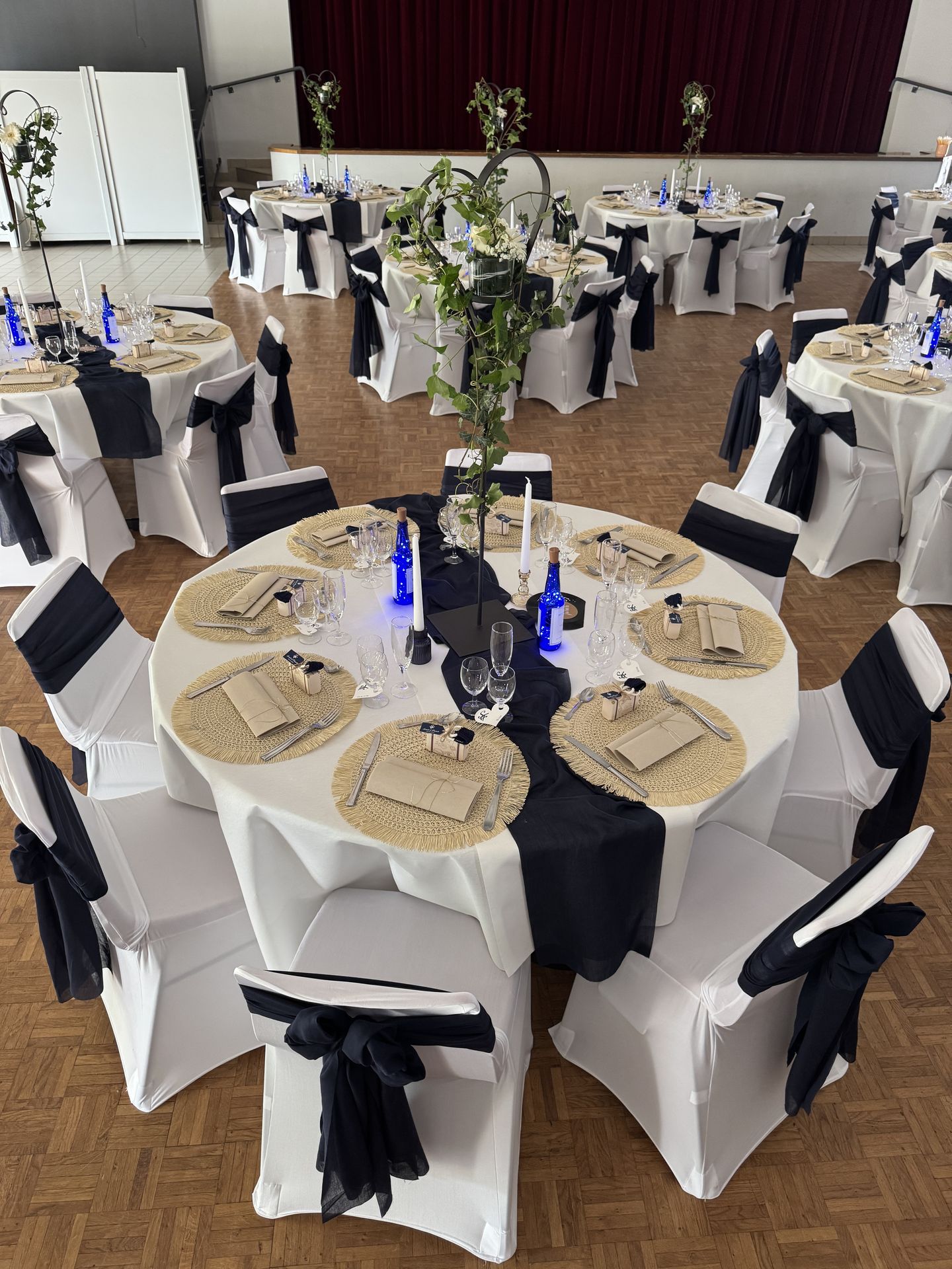 Mariage Espace de la Roche salle intérieur plafond tentures bleu marine et blanche leds table blanche noeud bleu marine et détails sables centr de table coeur feuillage