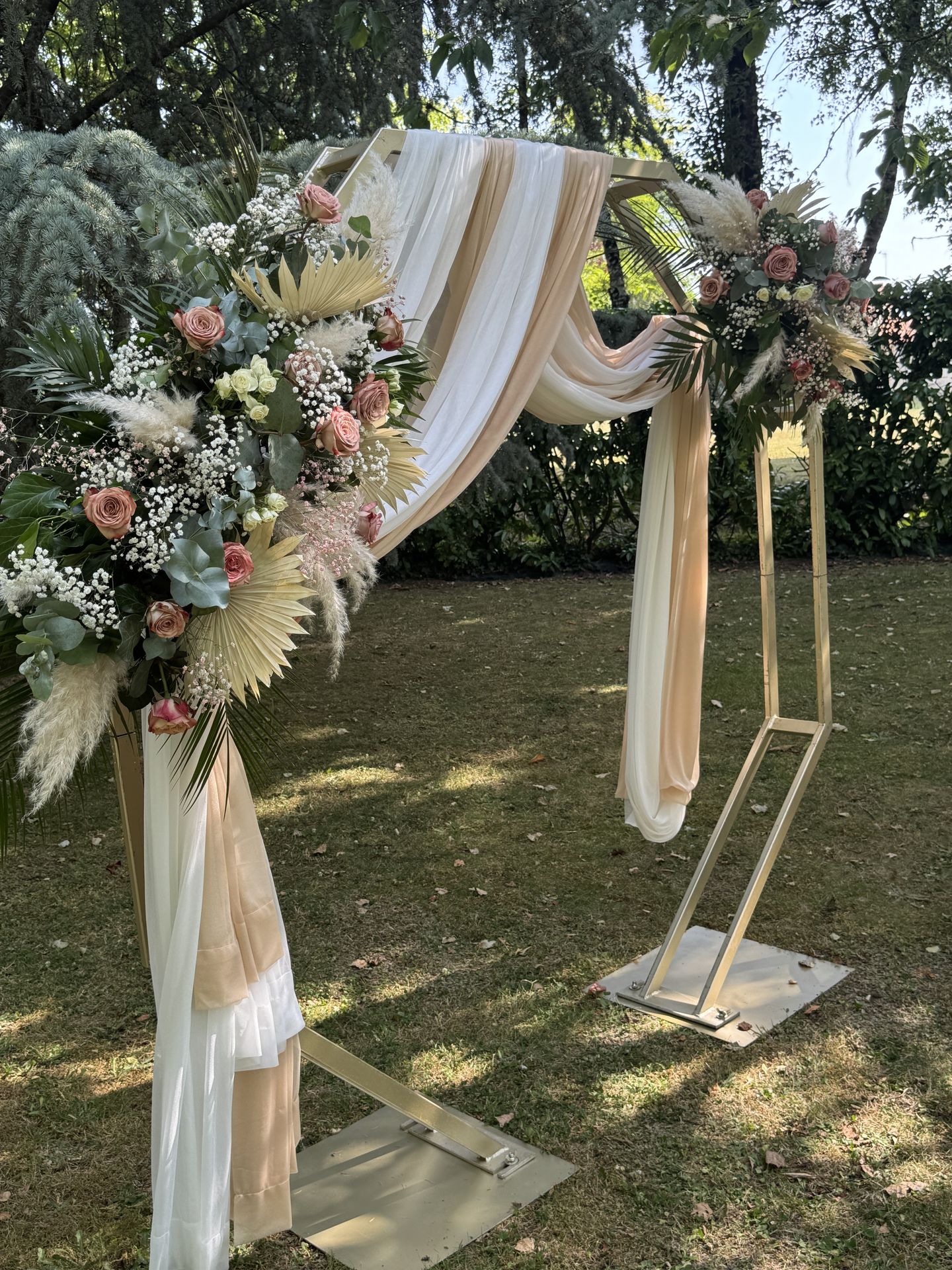 Mariage Salle des Audouins arche dorée tissu blanc sable composition florale