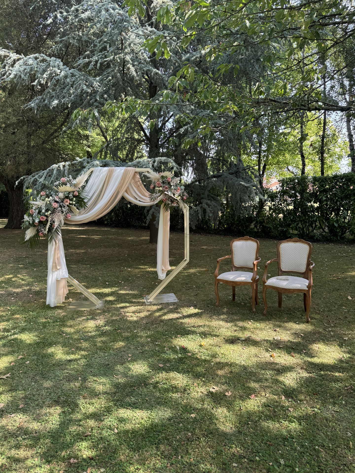 Mariage Salle des Audouins arche dorée tissu blanc et sable composition florale chaises blanche
