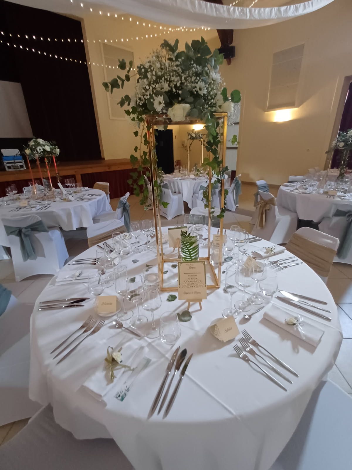 Mariage Salle des Fêtes table blanche marque place personnalisé composition florale menu de table impression noeud de chaise vert sauge et sable
