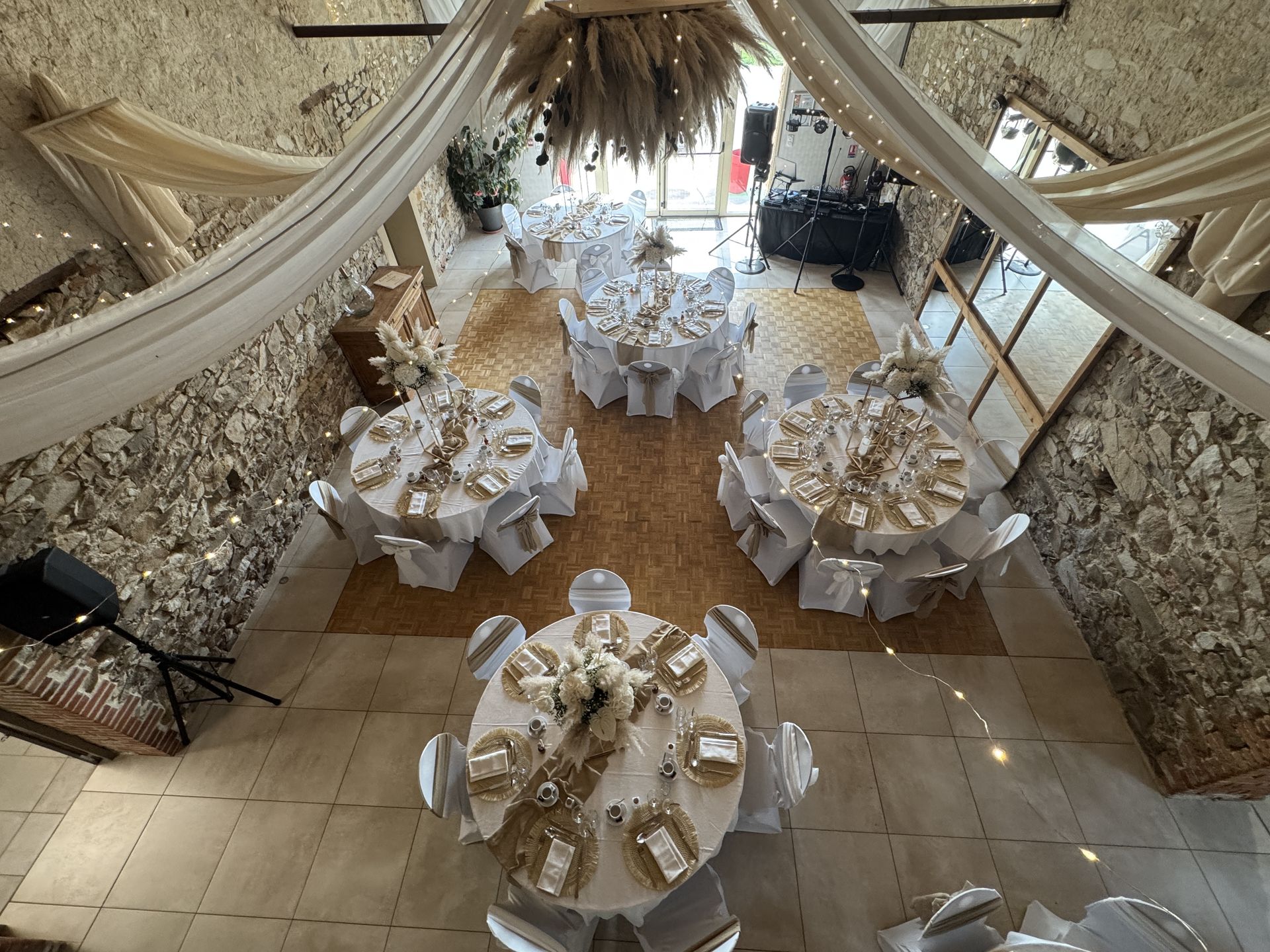 Mariage Domaine de Marin salle intérieure plafond tentures blanche leds et boule pampas table blanche et sable