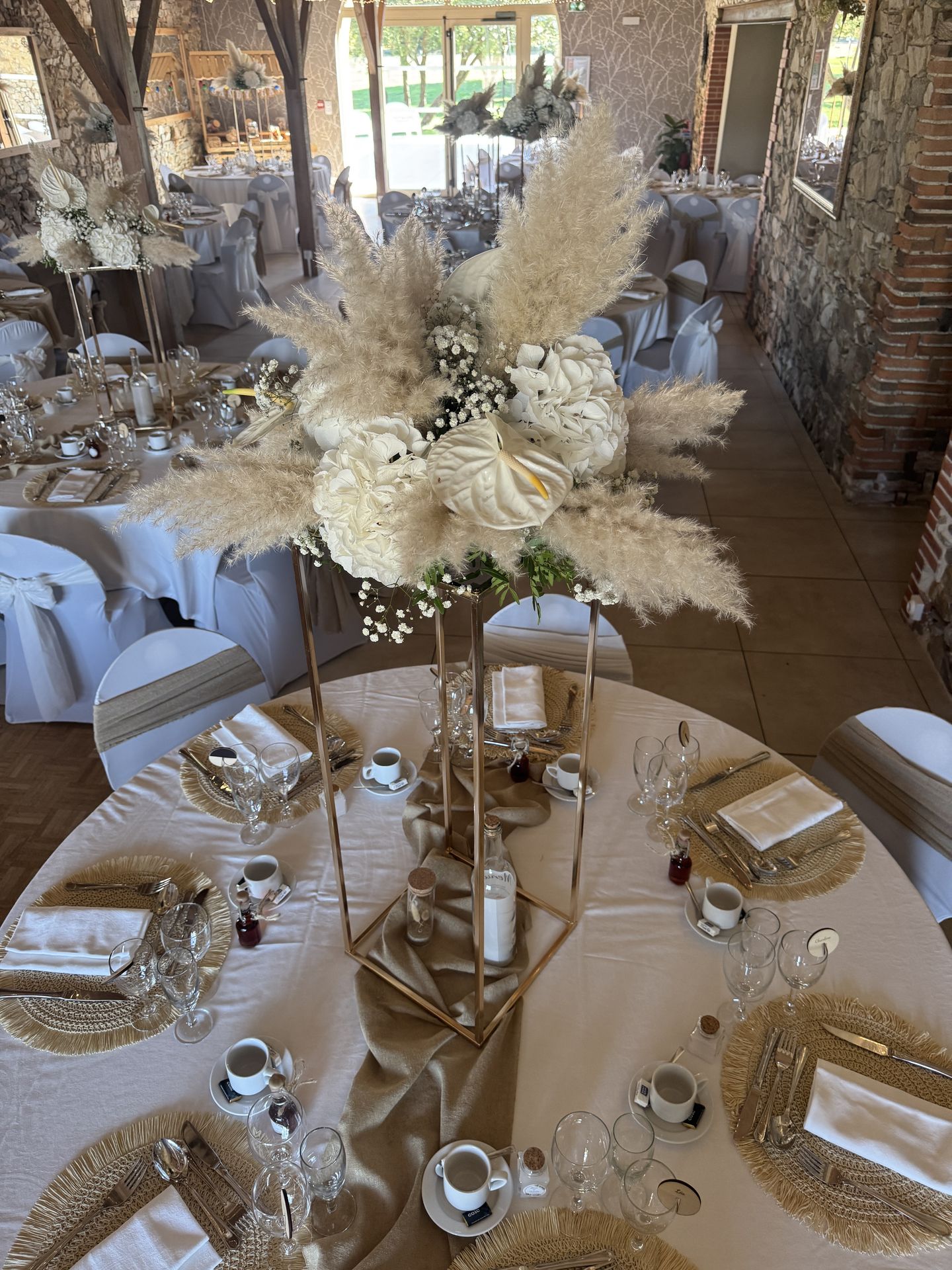Mariage Domaine de Marin salle intérieure table blanche et sable centre de table composition florale dessous de table en maille sable
