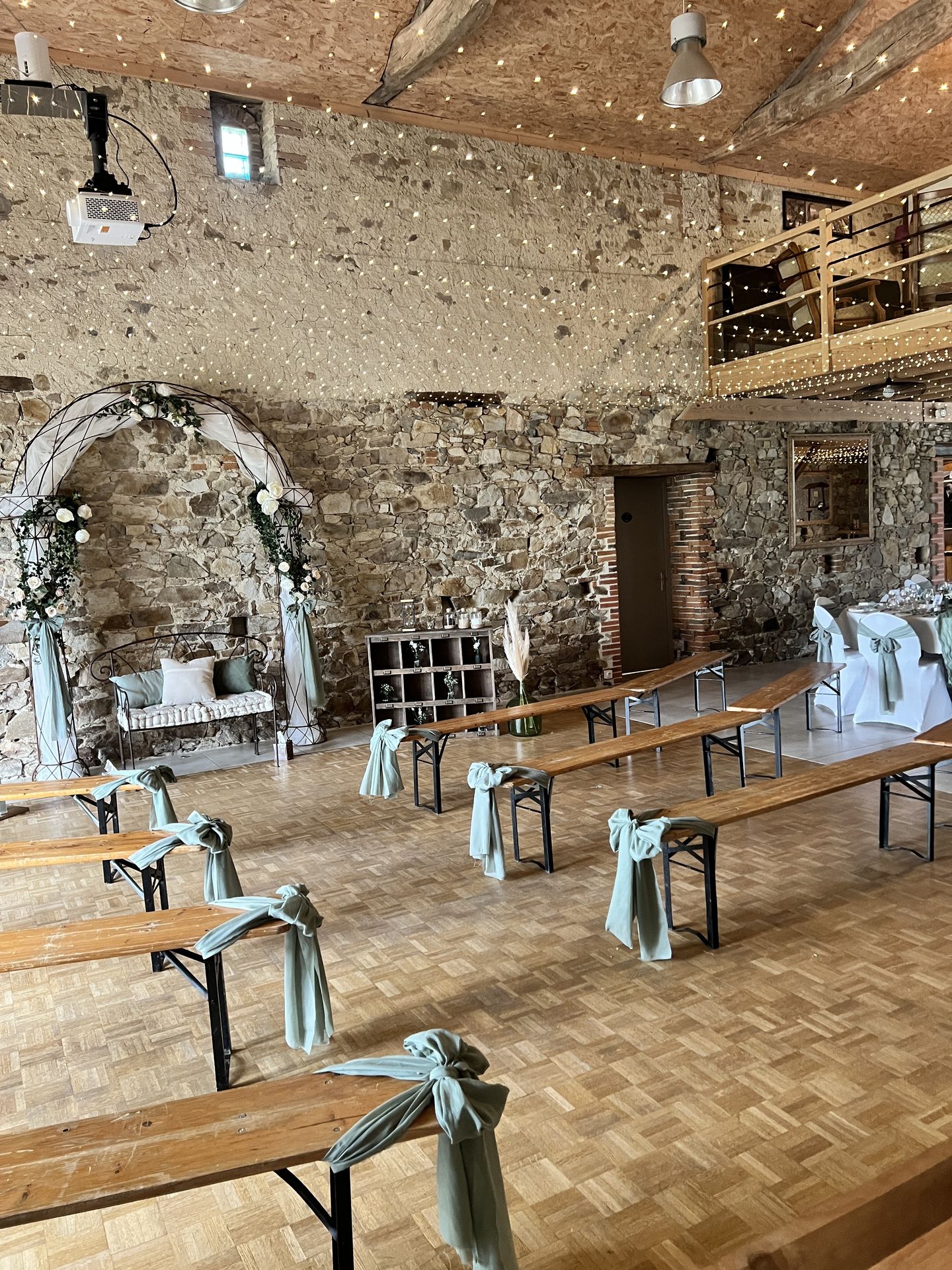 Mariage Domaine de Marin cérémonie laique intérieure banc noeud vert sauge arche arrondi tissu blanc canapé en metal composition florale