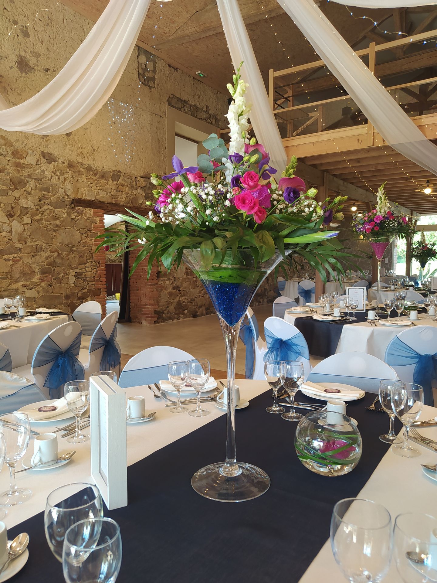 Mariage Domaine de Marin table blanches et bleu noeud de chaise bleu vase composition florale bleu rose feuillage cadre bois blanc