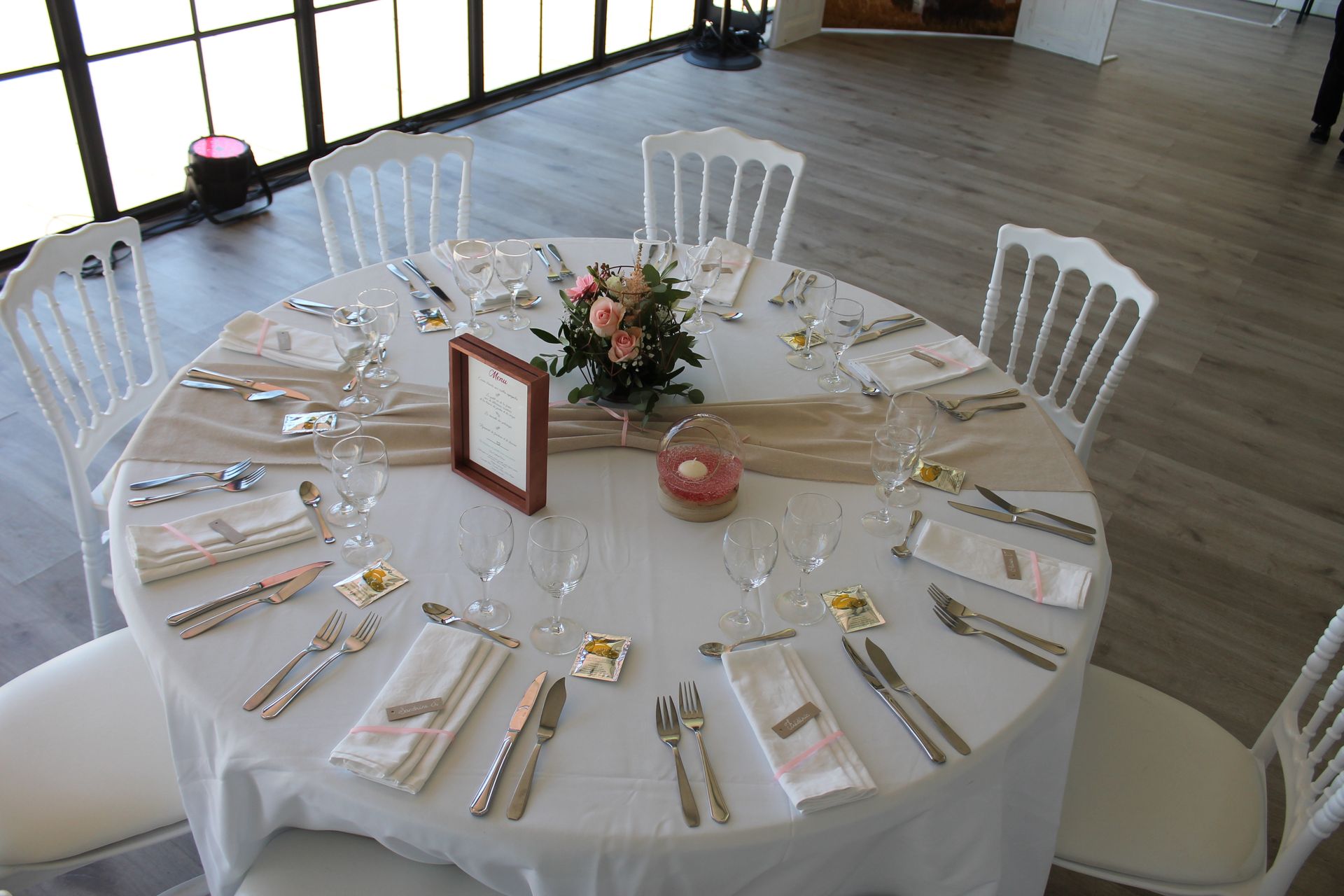Mariage Domaine de L'Oiselinière table blanche chemin de table sable composition florale et feuillage bougie vase eau rose numéro de table cadre rose