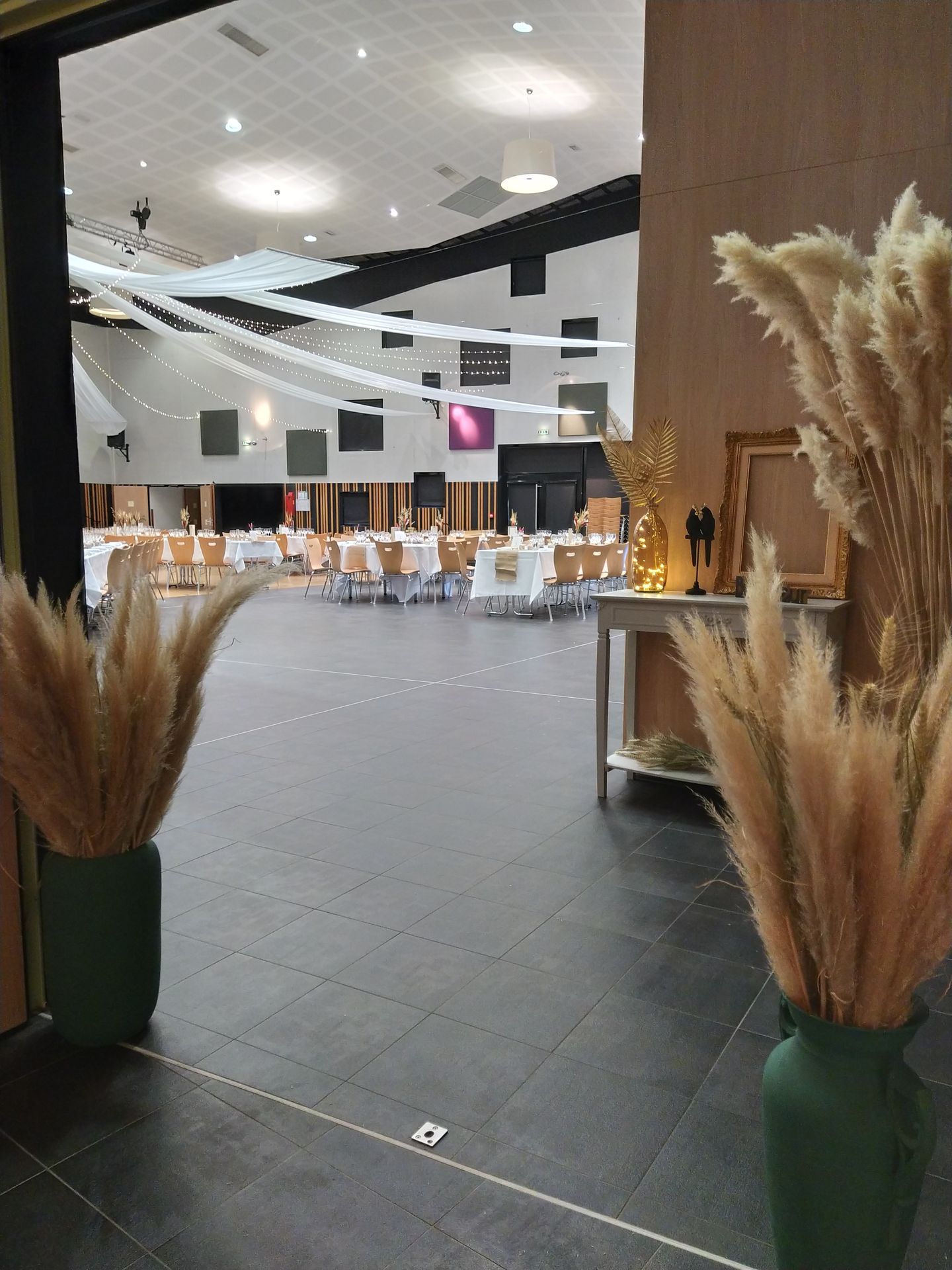 Mariage Espace du Doué plafond tentures blanches leds et boule chinoise en maille naturel table blanche vase vert pampas