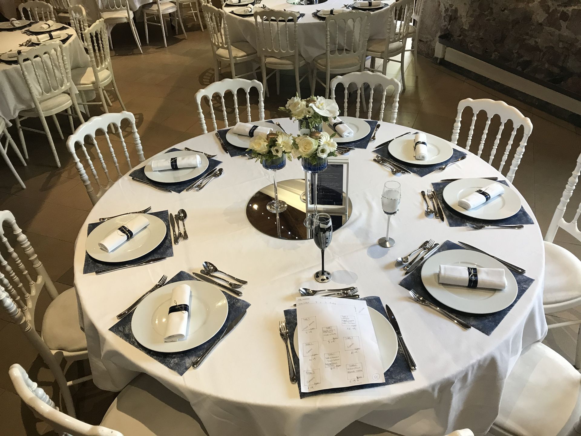 Mariage Château de la Galissonnière table blanche dessous de table bleu marine serviette blanche et noeud bleu marine centre de table miroir rond cadre menu blanc en bois et vase