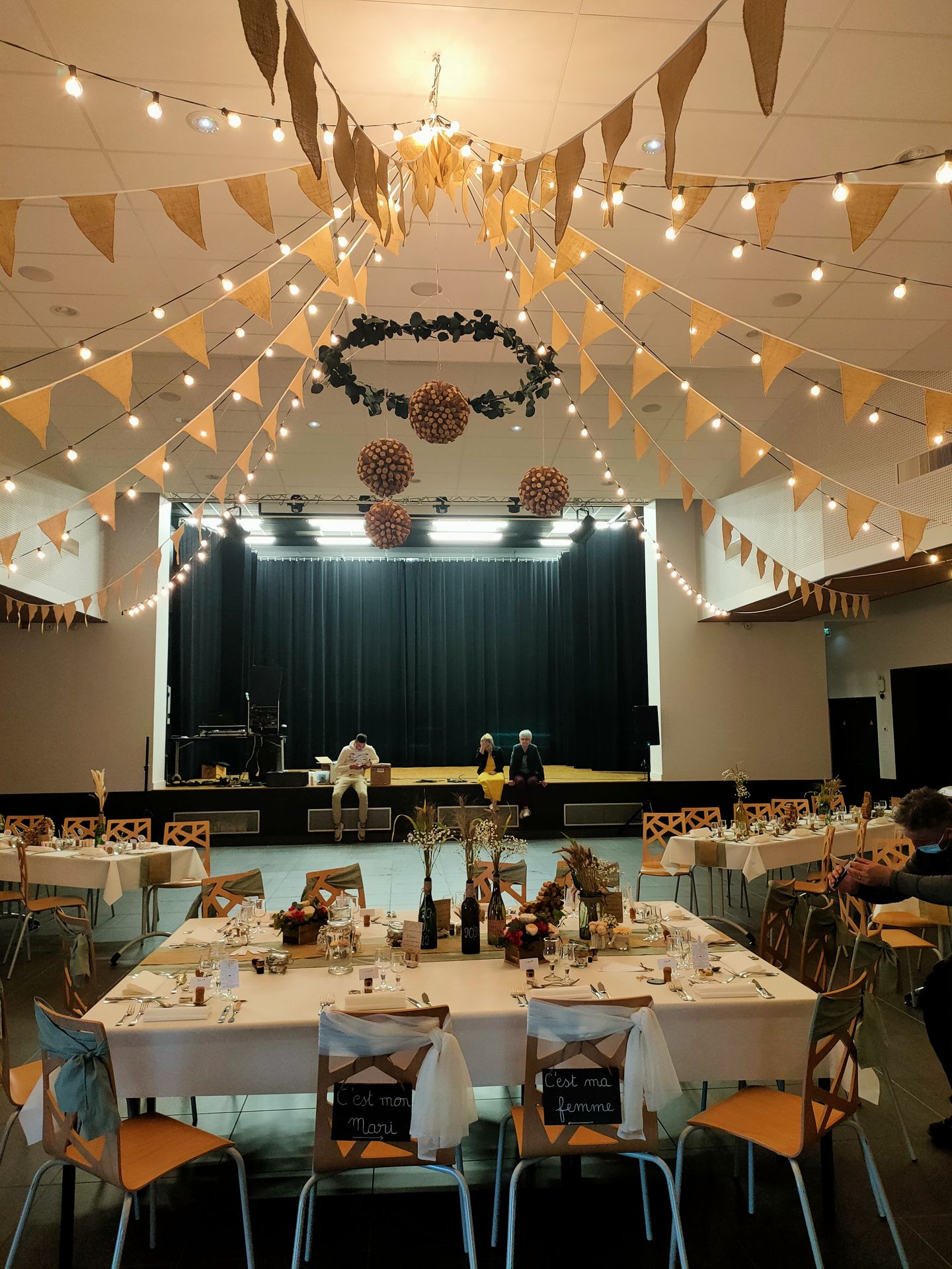 Mariage Salle Collinéa plafond guirlande guinguette fanion boule de bouchon de vin table blanche chemin de table noeud de cahise blanche et vert sauge vase fleurs sèches