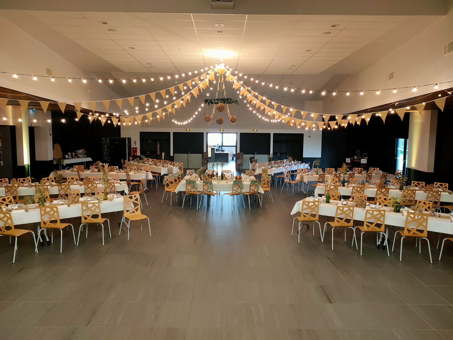 Mariage Salle Collinéa plafond guirlande guinguette fanion boule de bouchon de vin table blanche chemin de table noeud de cahise blanche et vert sauge vase fleurs sèches