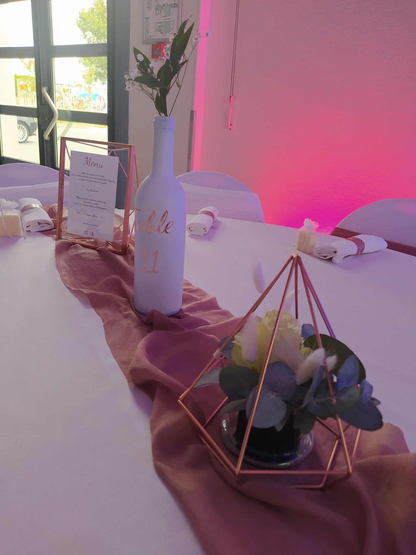 Mariage Salle des Fêtes centre de table vieux rose structure rose et fleurs cadre rose menu de table nom de table bouteille blanche