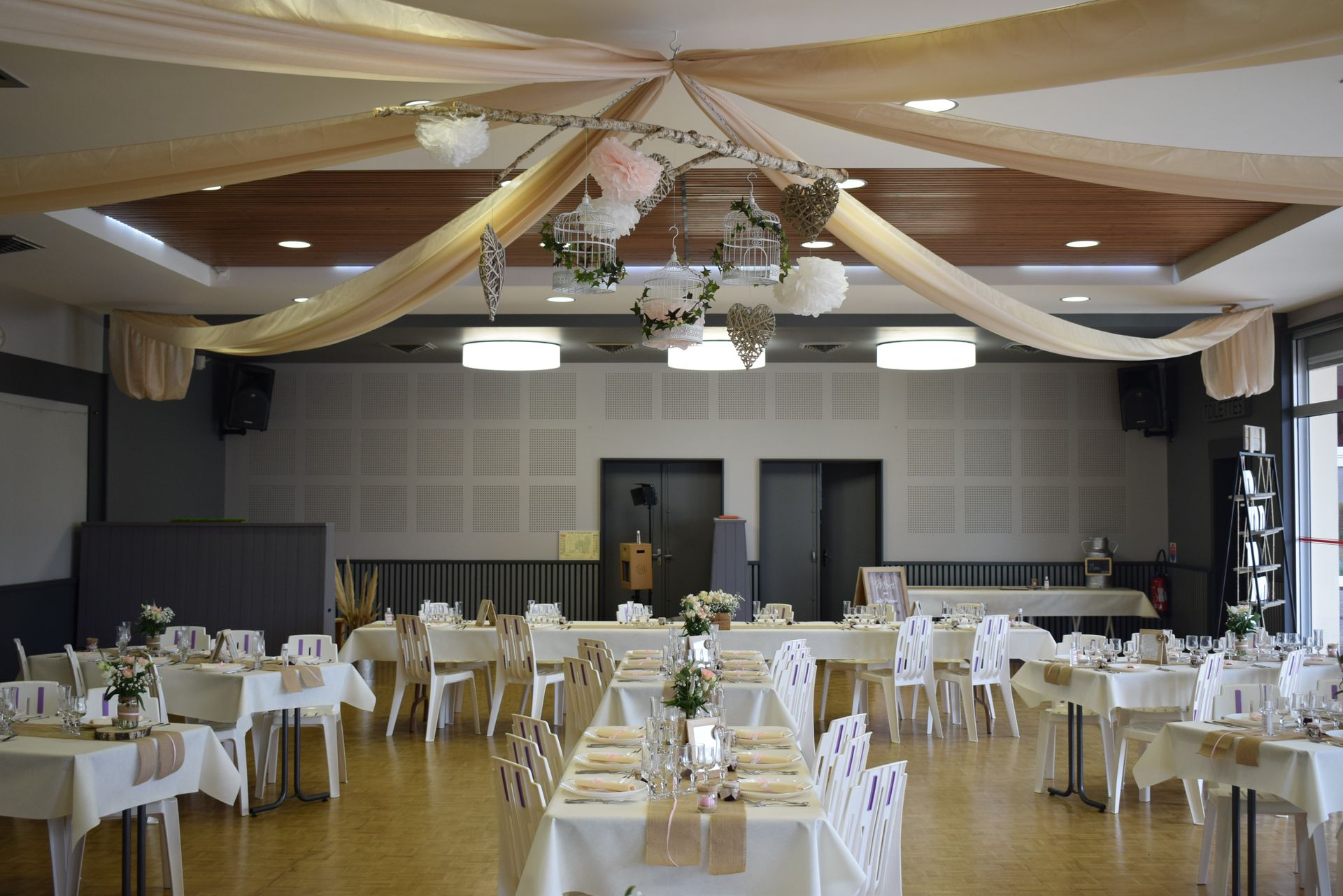 Mariage Salle L'Arc en Ciel plafond tentures sables structure bois cage blanche lière fleurs rose et blanche table blanche et sable