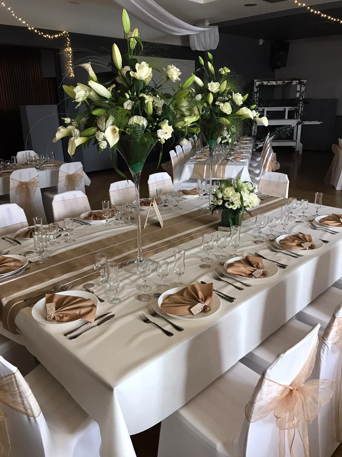 Mariage Salle L'Arc en Ciel table blanche chemin de table sable vase composition florale feuillage fleurs rose serviette sable et marque place menu de table cadre en bois