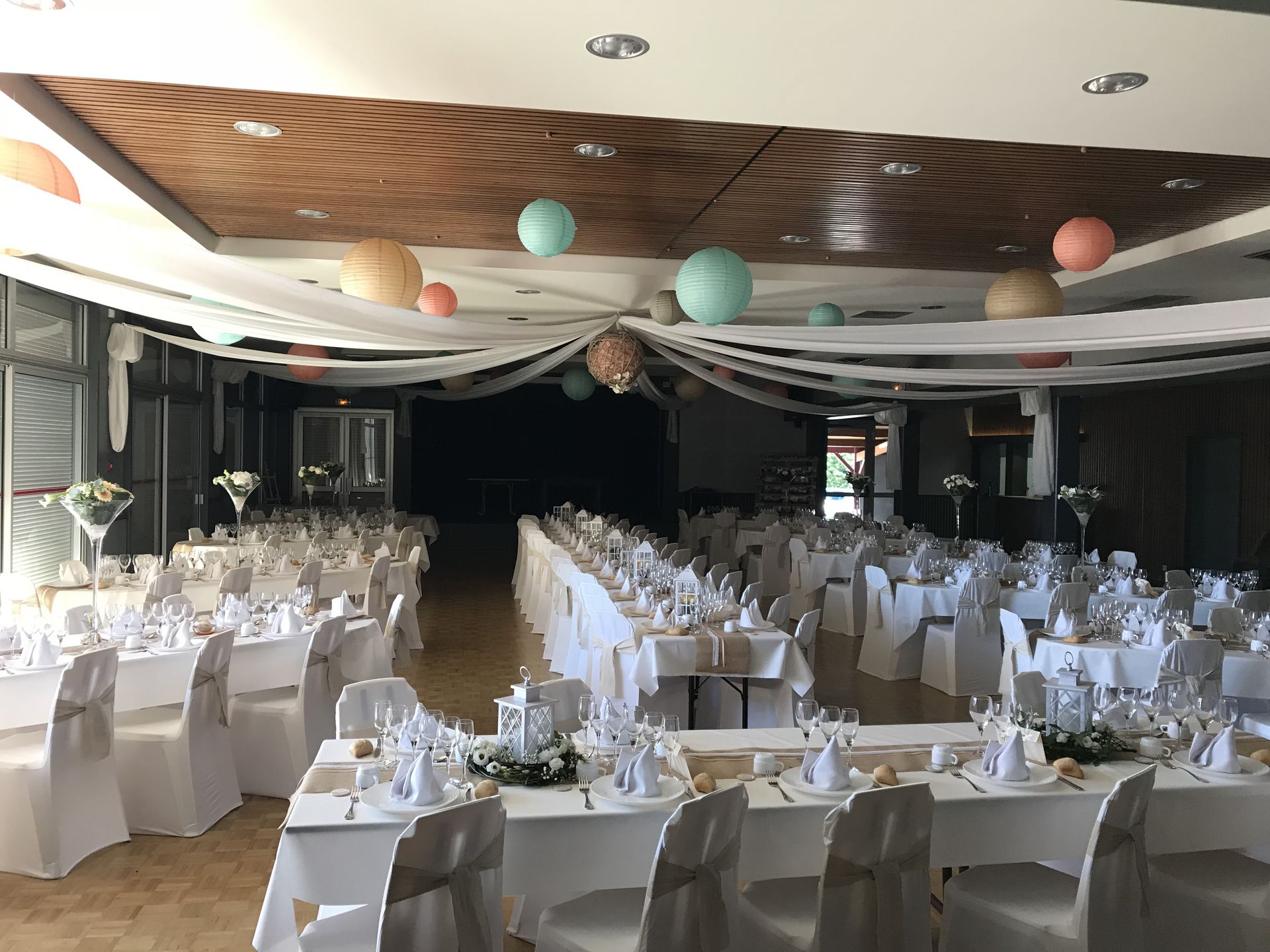 Mariage Salle L'Arc en Ciel plafond tentures blanche boule chinoise bleu rose et orange table blanche chemin de table sable lanterne blanc et composition florale