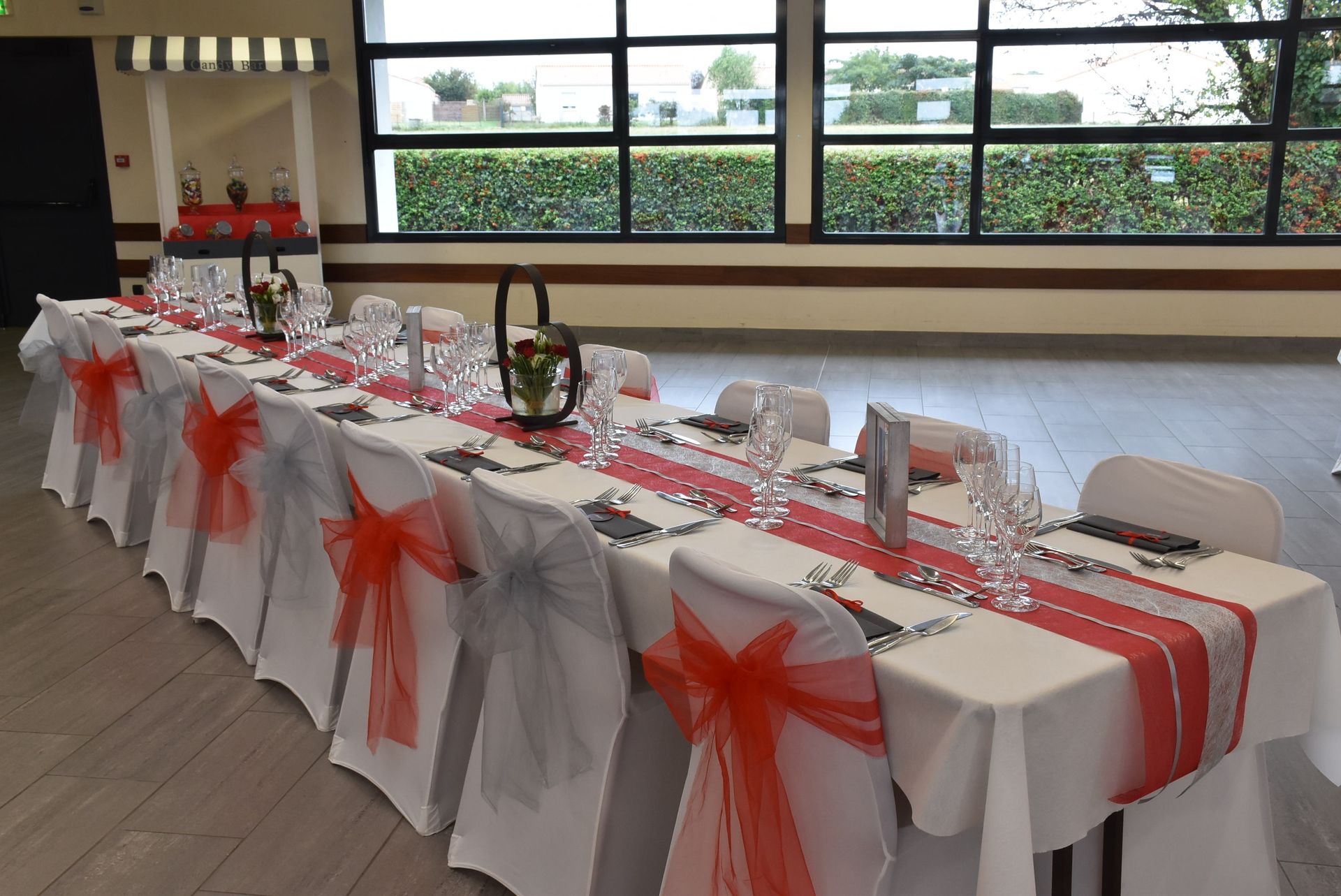 Mariage Salle du Bocage table blanche chemin de table rouge grise noeud de chaise rouge et grise coeur en métal argent cadre blanc en bois menu de table