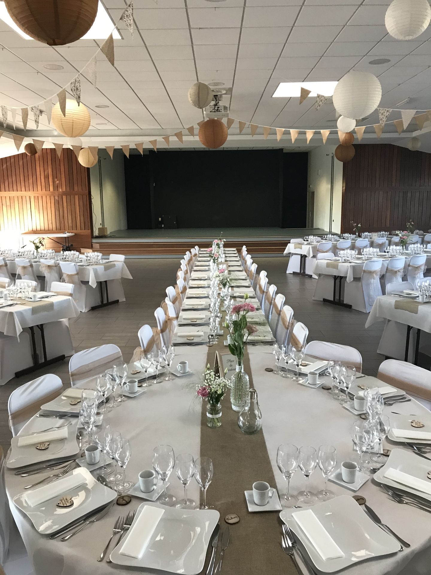 Mariage Salle du Bocage plafond guirlande fanion boule chinoise blanche beige marron table blanche chemin de table sable noeud de chaise marron cadeaux invités en bois