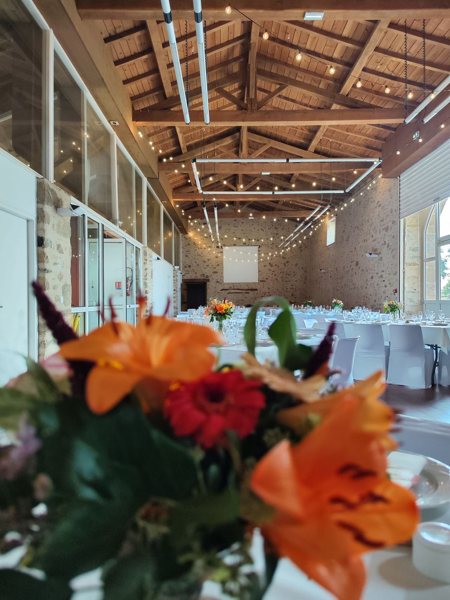 Mariage Salle de l'Etenduère plafond guirlande guinguette table blanche composition florale orange rouge feuillage