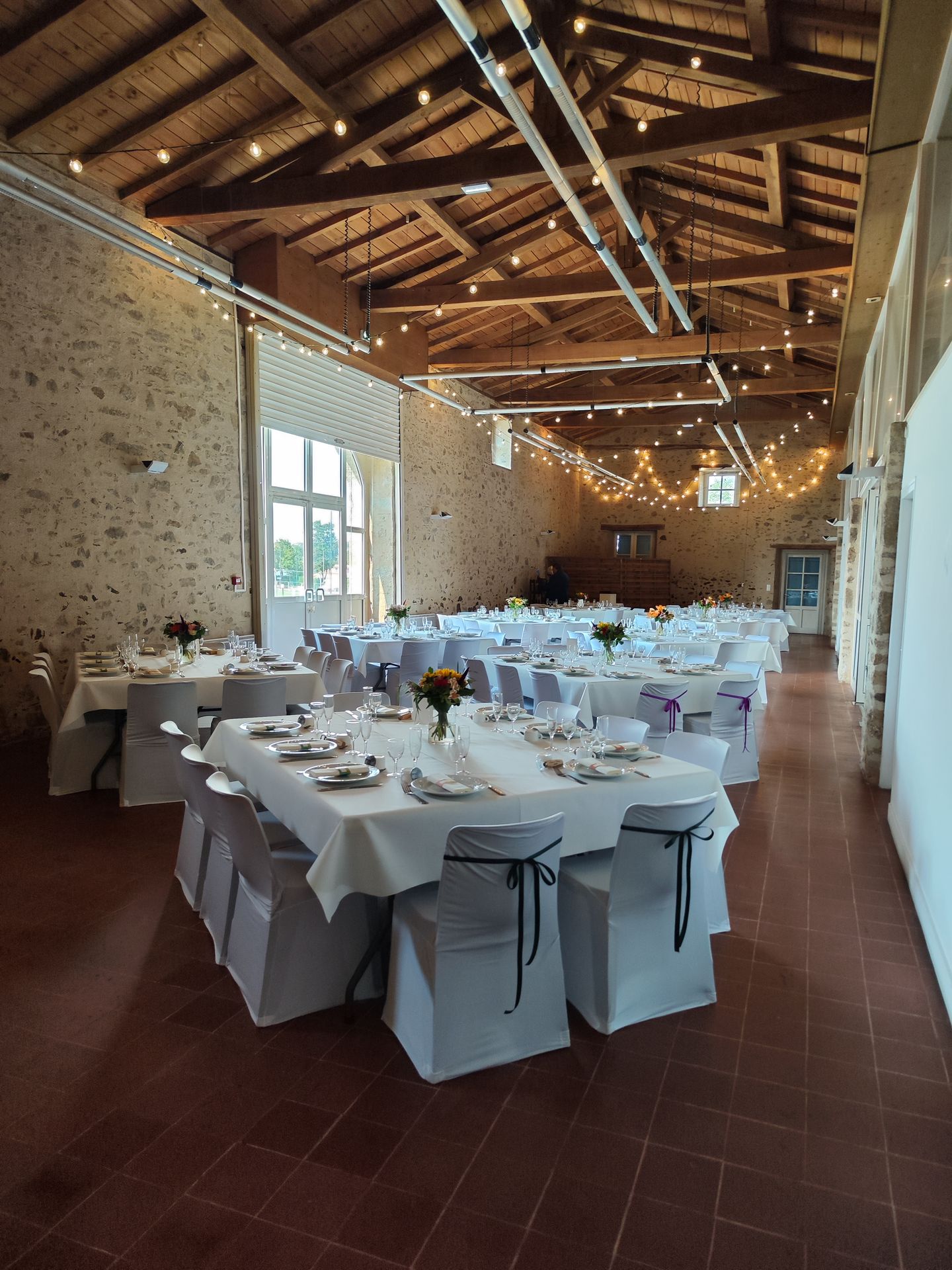 Mariage Salle de l'Etenduère plafond guirlande guinguette table blanche composition florale orange rouge feuillage noeud de chaisenoir