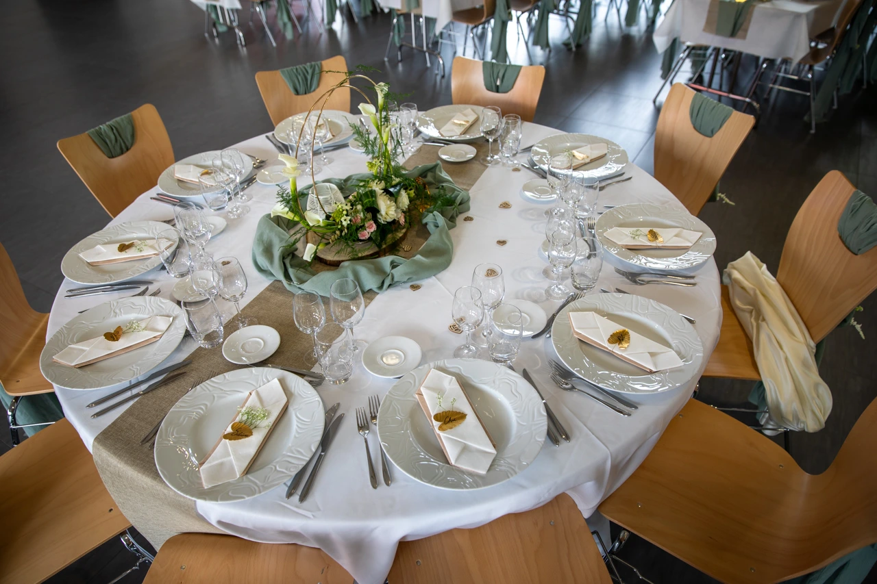 Mariage Salle Collinéa table blanche noeud de chaise vert sauge chemin de table sable composition florale rondin de bois tissu vert sauge