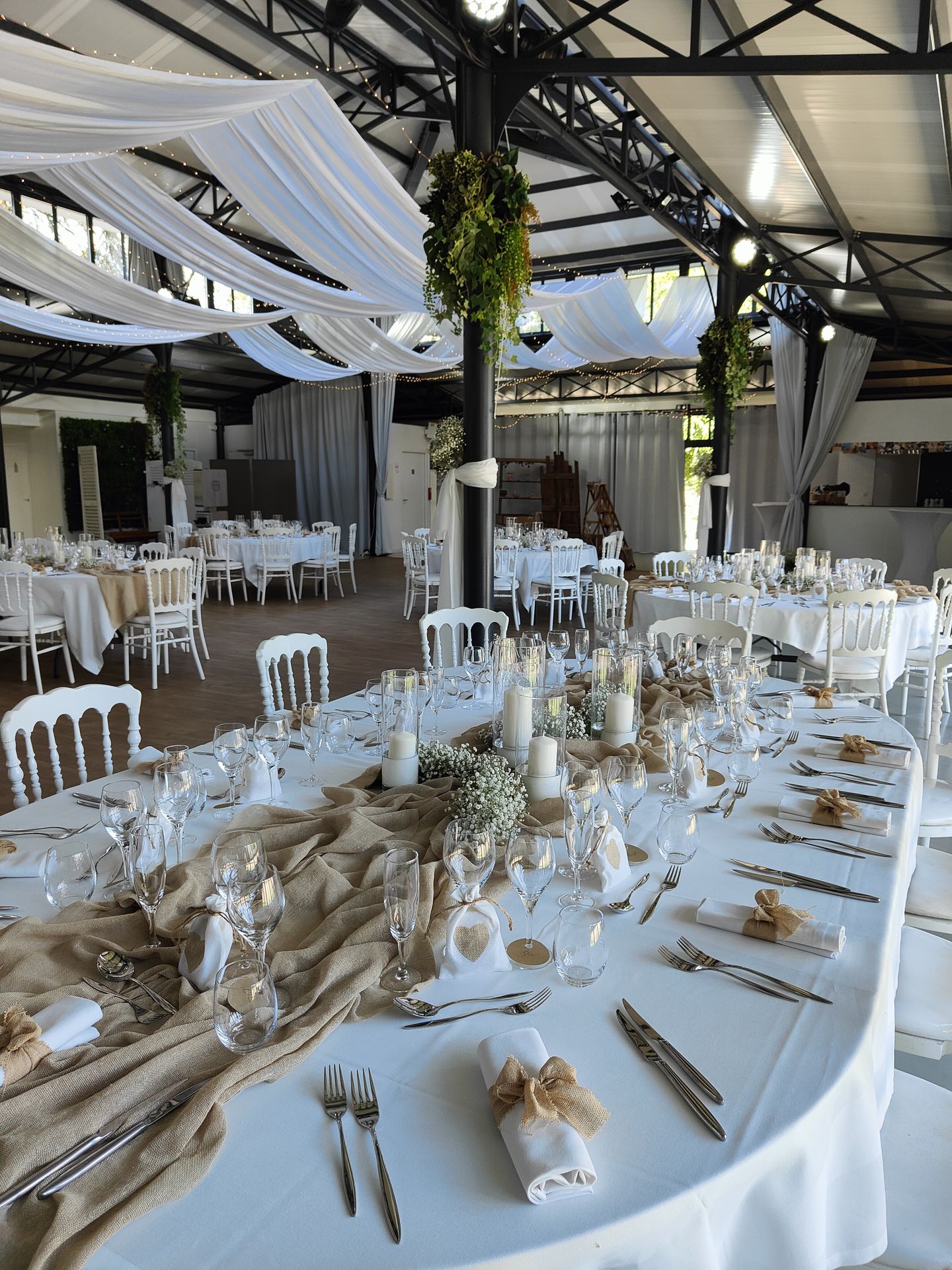 Mariage La Barbinière plafond tentures blanches et lière table blanche chemin de table sable noeud sable serviette vase bougie blanche composition florale blanche